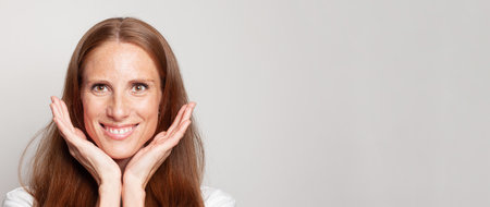 Beautiful mature female face close up. Perfect woman with fresh healthy skin with freckles on white...