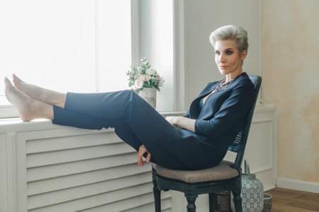 Blonde businesswoman sitting in the office with legs on windiwsillの写真素材