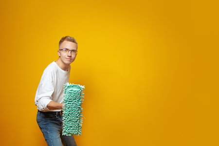 Cleaning man. Happy man with mop on bright orange background