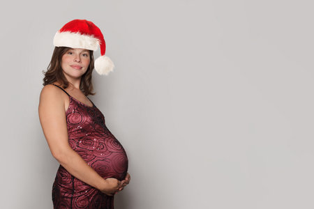 Christmas portrait of cute  pregnant woman Santa. New Year, new lifeの写真素材