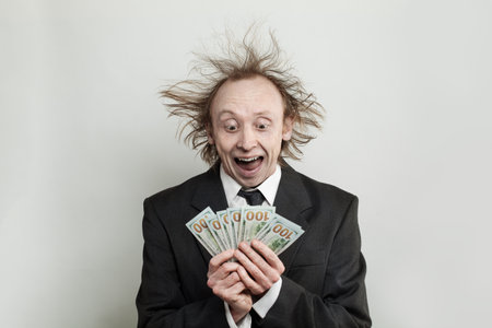 Happy excited businessman holding 100 US dollar banknote cash money on white background, studio...