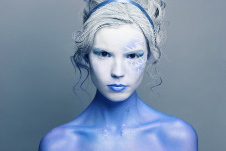 Devil woman with creative makeup on gray background, fashion portrait
