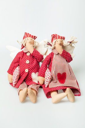 Two doll man and woman in red pajamas dress holding pillow and yawning on white backgroundの写真素材