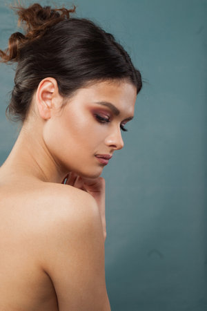 Charming healthy fenale model with clear fresh skin. Brunette woman with dark hair on blue backgroundの写真素材