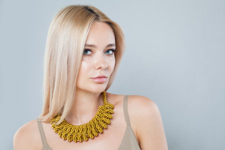 Attractive fashion model woman with clear fresh perfect skin and long blonde hair wearing yellow...