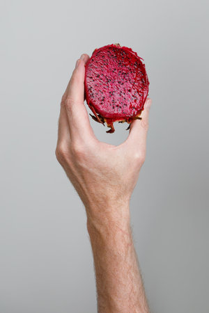 Half of Ripe Dragon fruit, Pitaya or Pitahaya in human hand on gray background, healthy food conceptの写真素材
