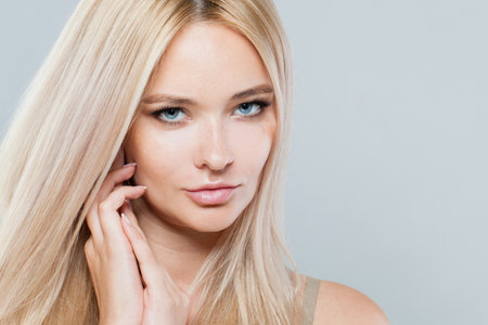Perfect woman face close-up. Blonde model with fresh clear skin and healthy silky hair on white backgroundの写真素材