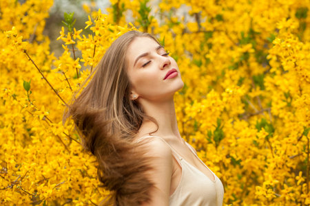 Attractive spring woman fashion beauty portrait. Young model with make-up and long hair in blossom...