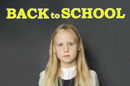 Adorable little girl child elementary student with yellow Back to school inscription on blackboard...