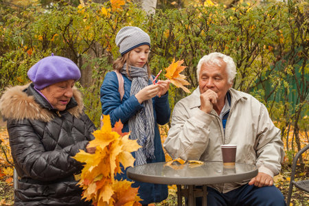 Happy grandfather, grandmother and granddaughter, outdoor autumn portraitの写真素材