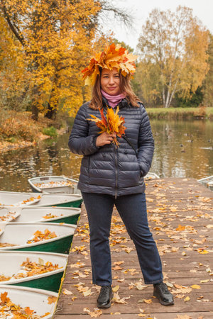 Walking woman in yellow leaves wreath outdoors on autumn background, portraitの写真素材