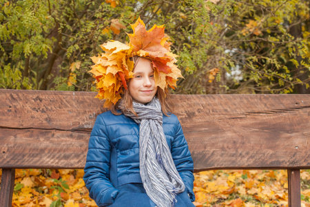 Cute child girl with yellow and orange autumn leaves outdoor