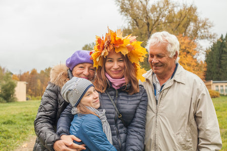 Autumn family portrait. Senior man and woman, mid adult woman and child girl outdoorの写真素材