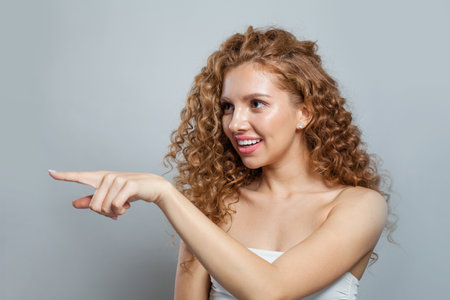 Emotional young cute woman pushing button or pointing finger a side on white background with copy spaceの写真素材