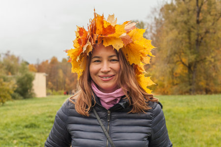 Joyful smiling woman in yellow leaves wreath outdoor on autumn background, portraitの写真素材
