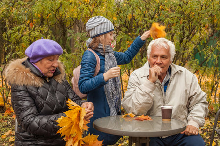 Grandfather and grandmother outdoors with granddaughter in autumn