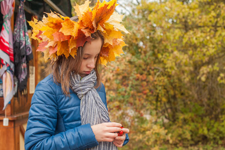 Portrait of cute child girl in autumn leaves wreath in fall parkの写真素材