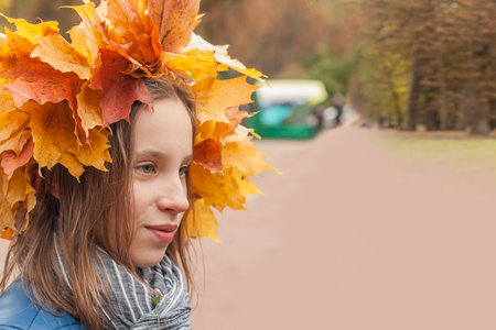 Young child girl in autumn leaves wreath outdoorsの写真素材