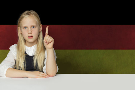 Blonde young child girl on German flag background. Education and study language in Germany conceptの写真素材