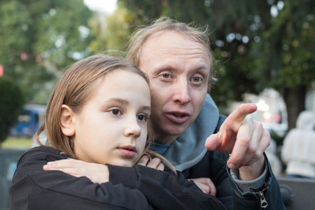 Close-up portrait of daughter child girl and her father together looking at something and pointing. Happy family, leisure activity, weekend and vacation conceptの写真素材