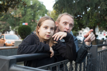 Cheerful daughter child girl and her father together looking at something and pointing. Happy family, leisure activity, weekend and vacation conceptの写真素材