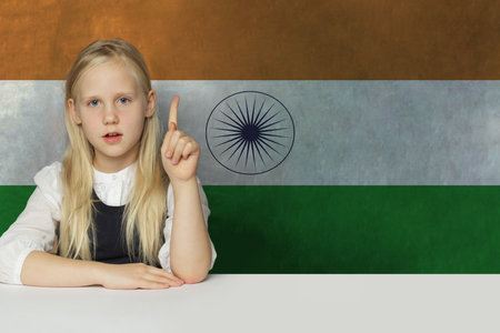 Adorable young child girl pointing up on flag of India background. Education and study language...