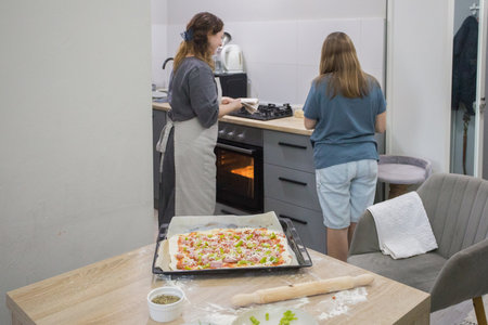 Family cooking homemade pizza in domestic kitchen together. Mother and daughterの写真素材