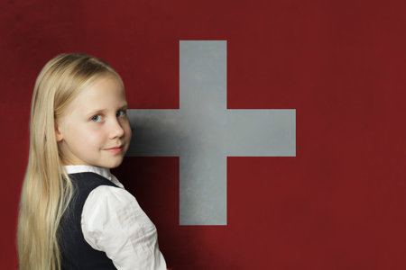 Happy young child girl on flag of Switzerland background. Education and study language conceptの写真素材