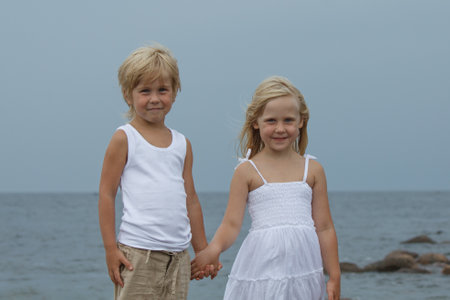 Happy blond little girl and boy holding each others handsの写真素材
