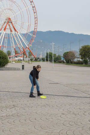 Kid 11 years old young girl catching flying disc and having fun outdoors. Happy childhood, sport and leisure activity conceptの写真素材