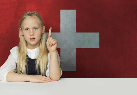 Curious young child girl pointing up on flag of Switzerland background. Education and study language conceptの写真素材
