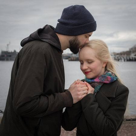 Smiling young woman with long blonde hair and man couple hugging each other kissing at seasideの写真素材