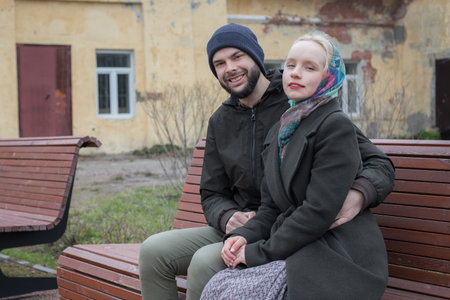 Cheerful woman and man sitting on a bench. Boyfriend and girlfriend outdoors. Happy coupleの写真素材