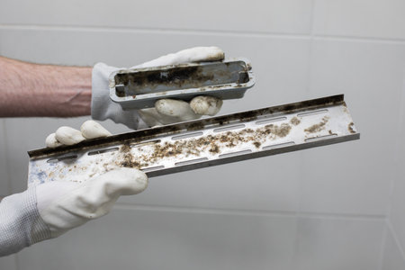 Hygiene Bathroom problem. Bathroom drain with mildew and dirt in plumber hands close-upの写真素材