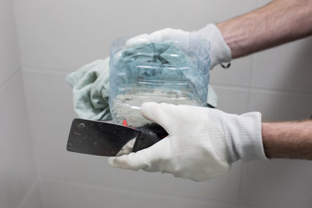 Trowel and cement glue for bathroom renovation work in male hands close upの写真素材
