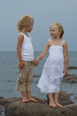 Playful blond little girl and boy standing outdoors, portraitの写真素材