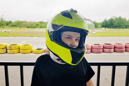 Happy child in helmet go-karting on a motor racing trackの写真素材
