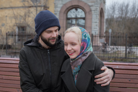 Smiling woman and man sitting on a bench. Boyfriend and girlfriend outdoors. Happy coupleの写真素材