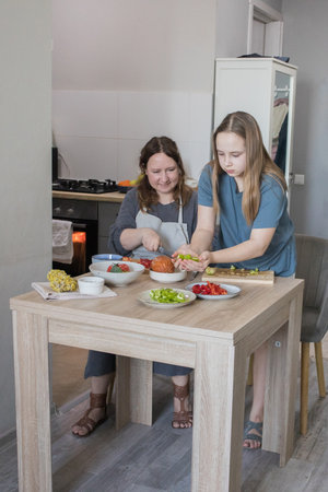 Family together. Mother teaching daughter how to prepare vegetablesの写真素材