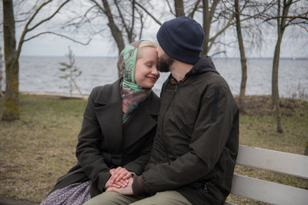 Attractive woman and man sitting on a bench. Boyfriend and girlfriend outdoors. Happy coupleの写真素材