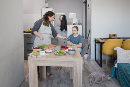 Child daughter and her mother cooking in domestic kitchen together, family lifestyle portraitの写真素材
