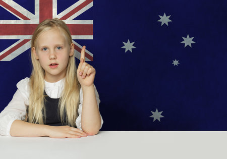 Cheerful young child girl pointing up on flag of Australia background. Education in Australia conceptの写真素材