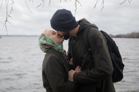Portrait of man and young blond woman couple hugging each other kissing at seasideの写真素材