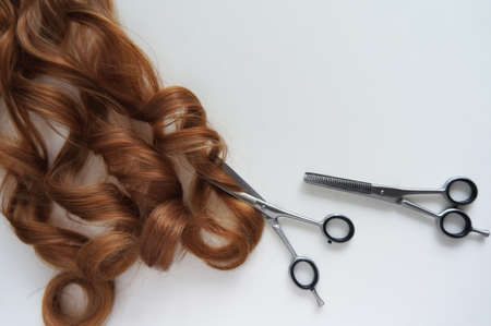Long brown hair with scissors on close up on white backgroundの写真素材