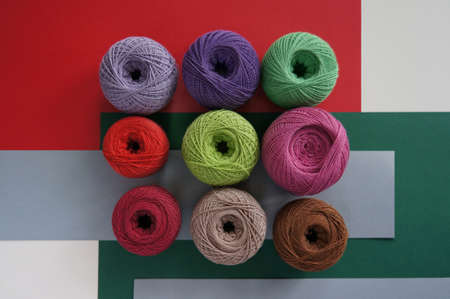 yarns of threads for knitting in different colors on a red green background 