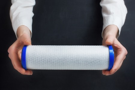 water filter cartridge in human hands on blackの写真素材