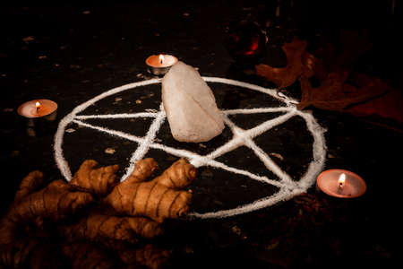 Pentagram made of salt, a symbol used for protection,  surrounded by candles, herbs and spices in dim moody lighting.の写真素材