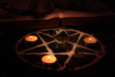 Pentagram made of salt, a symbol used for protection,  surrounded by candles, herbs and spices in...