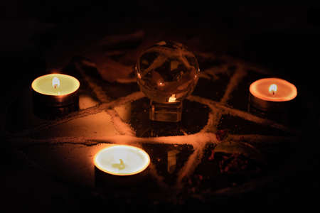 Pentagram made of salt, a symbol used for protection,  surrounded by candles, herbs and spices in dim moody lighting.の写真素材