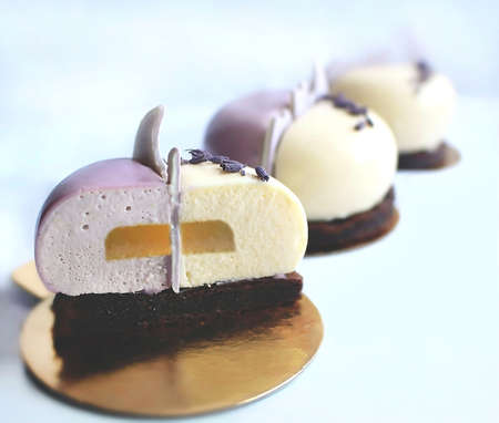 Purple and white dessert cut with yellow jelly inside on brownie baseの写真素材